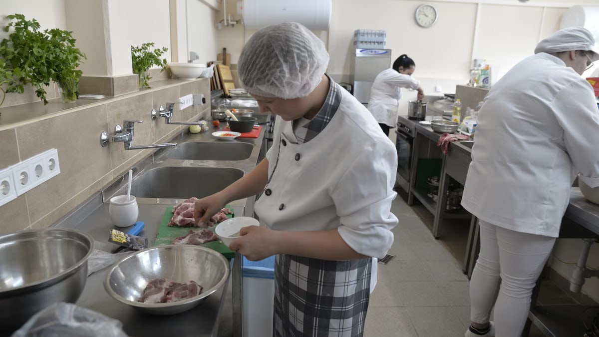 Culinary students practicing cooking skills in a professional kitchen setting, showcasing teamwork and education.